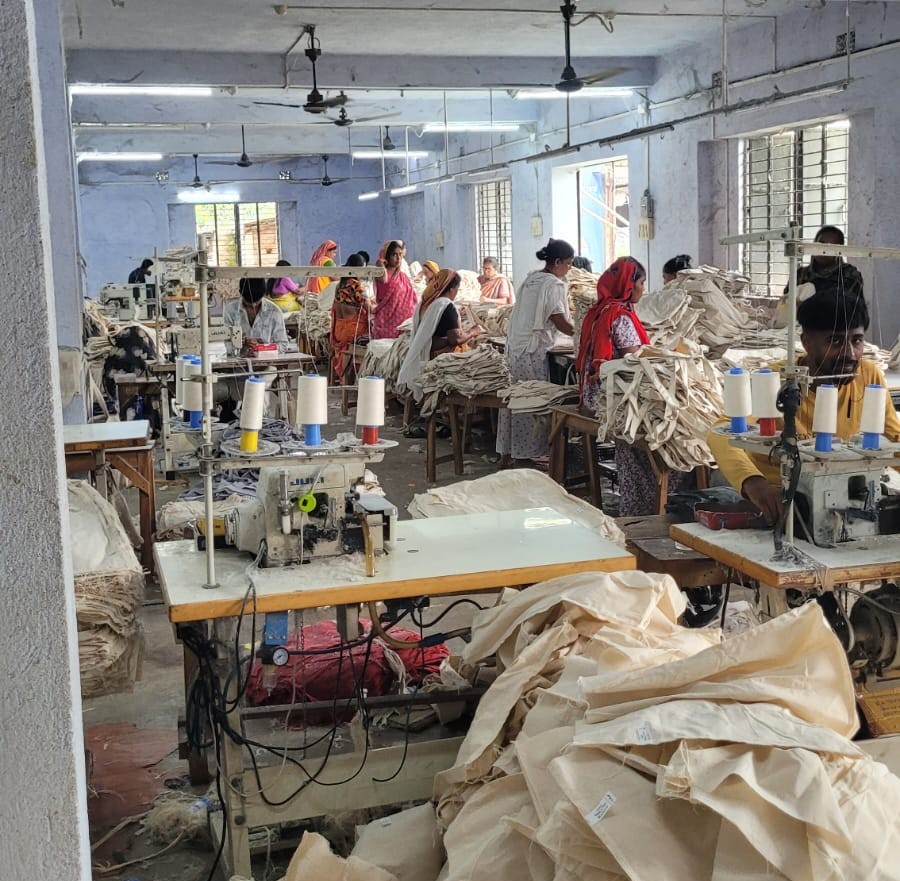 Artisans cutting raw jute fabric for bag production