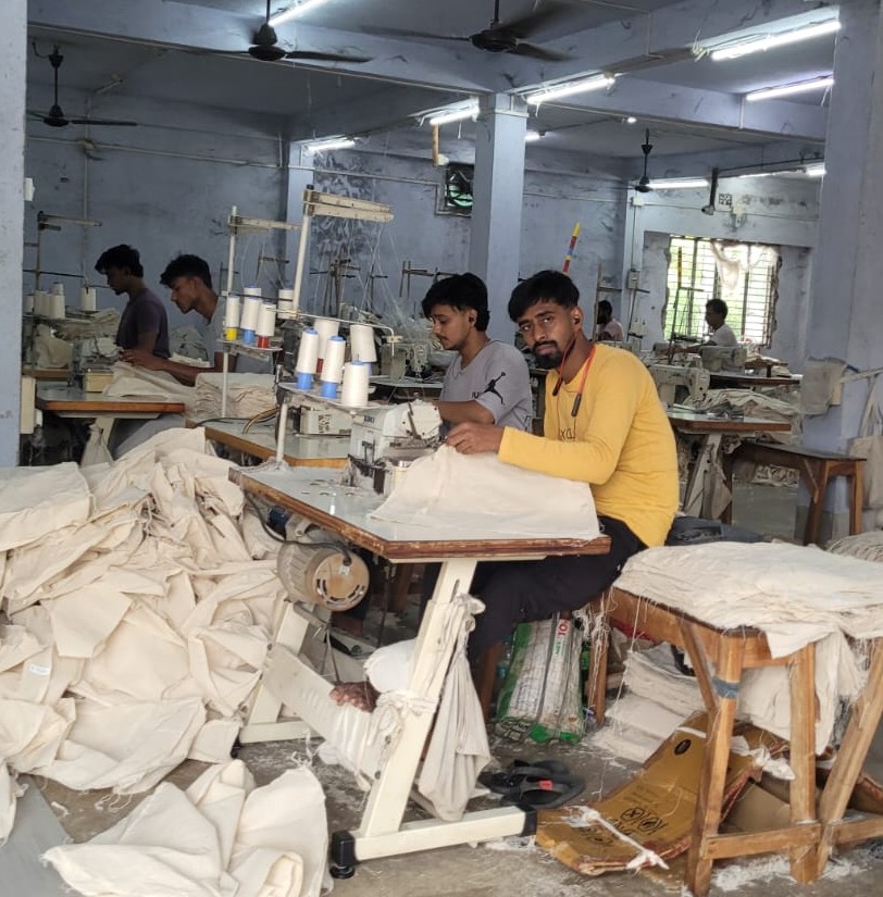 Artisans cutting raw jute fabric for bag production