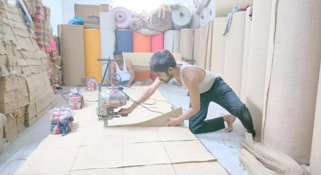 Artisans cutting raw jute fabric for bag production