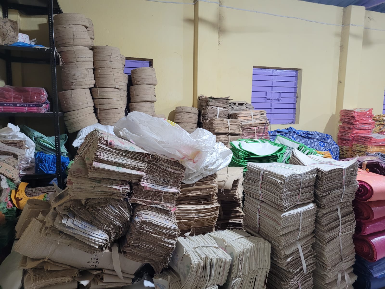 Artisans cutting raw jute fabric for bag production